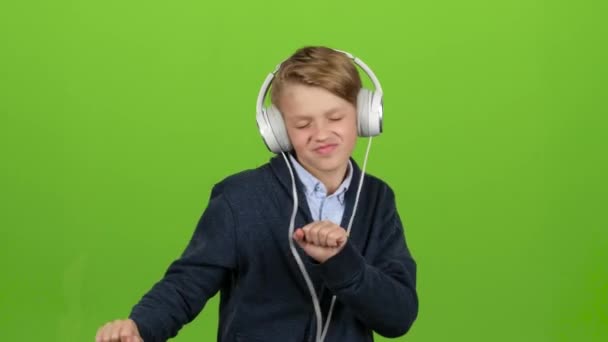 Il bambino con le cuffie sta ascoltando la musica. Schermo verde — Video Stock