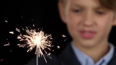 Çocuk bir maytap elinde tutuyor. Siyah arka plan. Yakın çekim