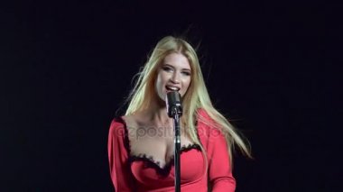Kırmızı elbiseli kız retro mikrofona şarkı söylüyor. Siyah arka plan