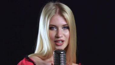 Kız dans ediyor ve retro bir mikrofon şarkı söylüyor. Siyah arka plan. Yakın çekim