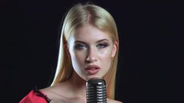 Şarkıcı restoranda retro bir mikrofon lirik bir şarkı söyler. Siyah arka plan. Yakın çekim