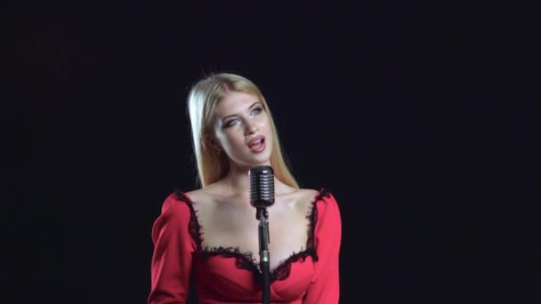 Dívka zpívá tichým hlasem v retro mikrofon. Černé pozadí — Stock video