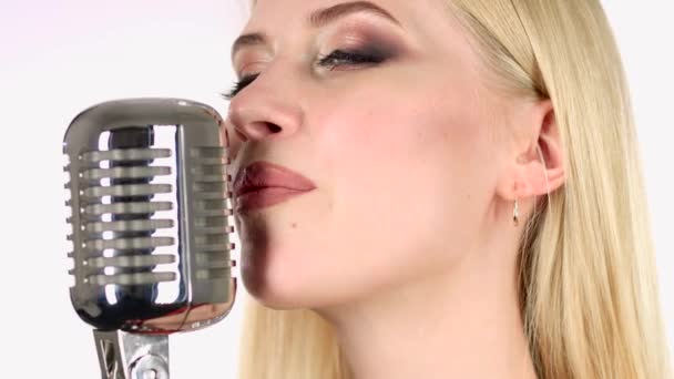 Κορίτσι που τραγουδάει σε ένα ρετρό μικρόφωνο. Λευκό φόντο. Πλαϊνή όψη. Κοντινό πλάνο — Αρχείο Βίντεο