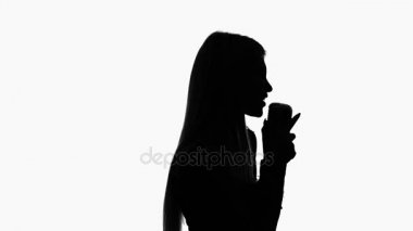 Vokalist giysili bir retro mikrofona şarkı söylüyor. Siluet. Yan görünümü. Beyaz arka plan