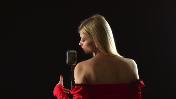 Chanteuse se tient avec son dos au public et chante. Fond noir — Video