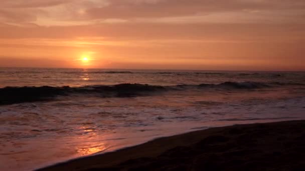 Vulkanen en enorme golven van de zee in de balken van een roze zonsondergang — Stockvideo