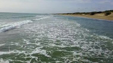 Sandy beach yoğun bulutlar gökyüzü kapsayan altında dalgalı kaba deniz ile. Hava anket. Ağır çekim