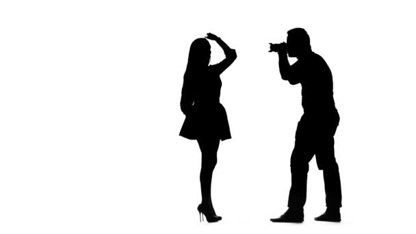 Model girl posing for a photographer. Silhouette. White background — Stock Video