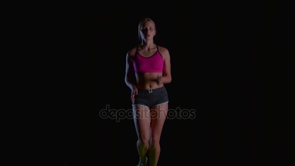 Молодая женщина бежит на черном фоне. Медленное движение — стоковое видео