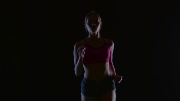 Meisje met blond haar wordt uitgevoerd op een zwarte achtergrond. Silhouet. Slow motion — Stockvideo