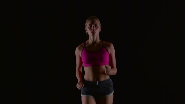 Mujer atleta corriendo contra en el fondo negro. Movimiento lento — Vídeos de Stock