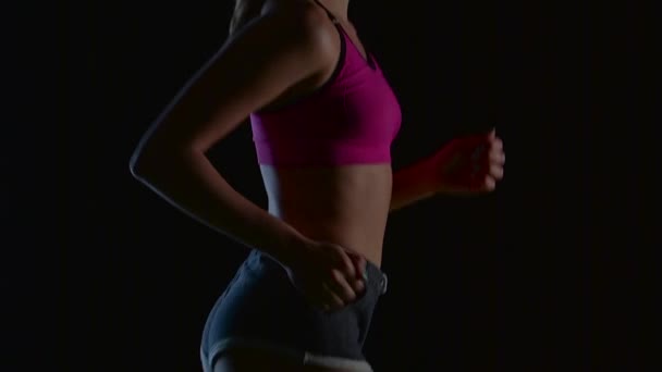 Female athlete running on a black background from the side. Slow motion. Close up — Stock Video