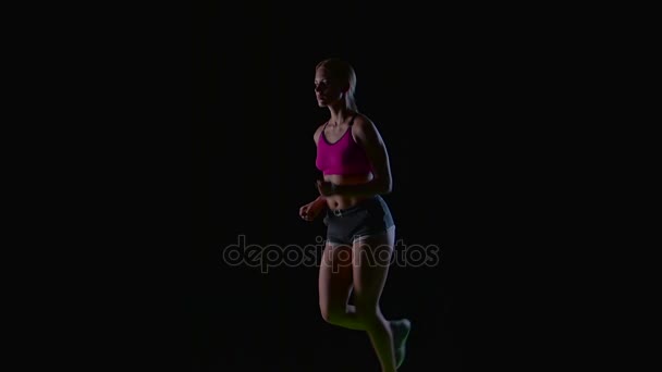 Спортивная фитнес-женщина, бегущая впереди на черном фоне. Силуэт. Медленное движение — стоковое видео