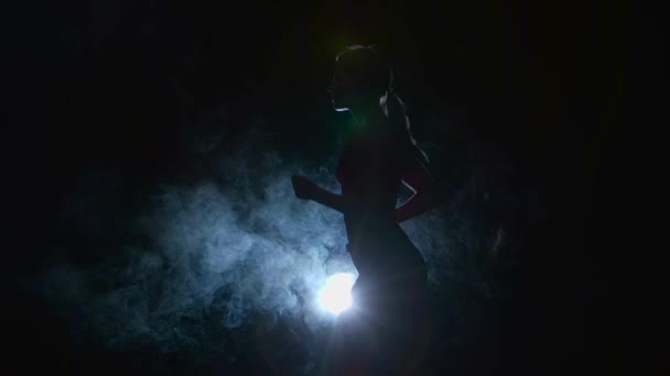 Atleta corriendo ligeramente sobre un fondo negro iluminado por el foco en el humo. Silueta. Movimiento lento — Vídeos de Stock