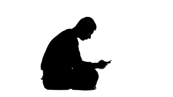 Man reads the information on the phone and is angry. White background. Silhouette — Stock Video