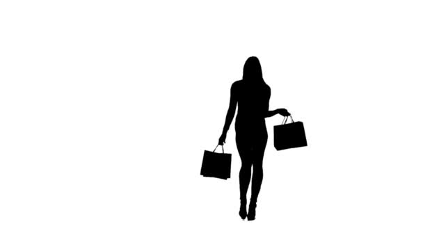 Woman with packages in hands posing for a camera, she is on high heels. Silhouette. White background. Slow motion — Stock Video