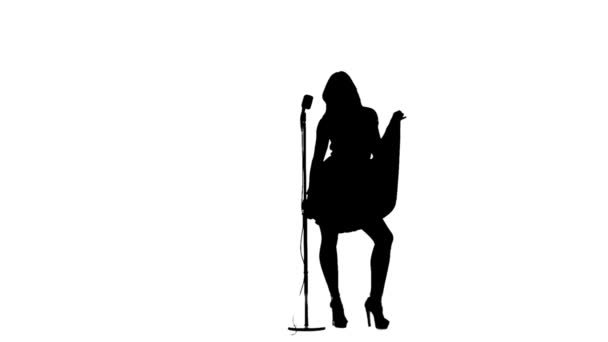 La mujer canta en un micrófono retro. Silueta. Fondo blanco. Movimiento lento — Vídeo de stock