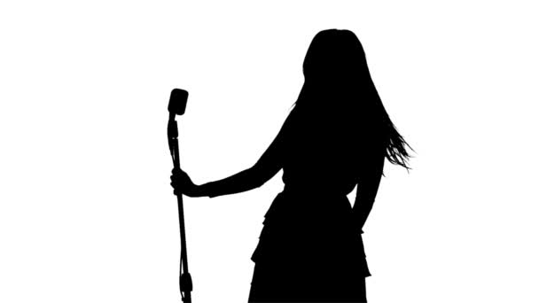 Singer está se movendo sexualmente no quadro com um microfone retro. Silhueta. Fundo branco. Movimento lento — Vídeo de Stock