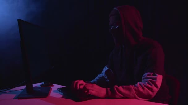 Шпион взламывает компьютер, сидя в темной комнате. Чёрный дым — стоковое видео