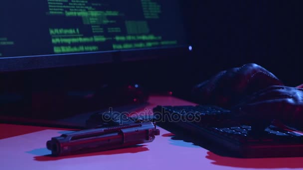 Hacker escribe los datos del virus, en la mesa hay una pistola. De cerca. — Vídeos de Stock