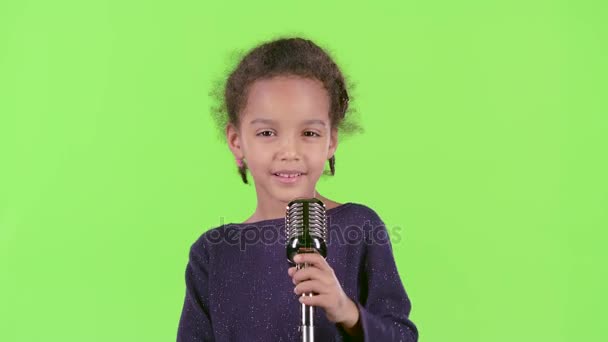 Bambino di una ragazza afroamericana che canta in un microfono retrò. Schermo verde — Video Stock