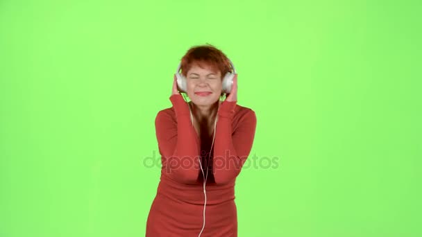 女性は、ヘッドフォンで音楽を聴きます。緑色の画面 — ストック動画