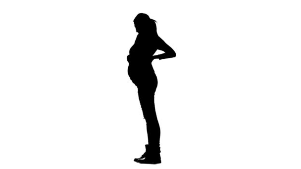 Une femme enceinte se tient debout et caresse son estomac. Silhouette. Fond blanc. Mouvement lent — Video