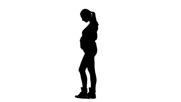 Dziewczyna w ciąży jest stały i głaszcząc jej żołądek. Sylwetka. Białe tło. Zwolnionym tempie — Wideo stockowe