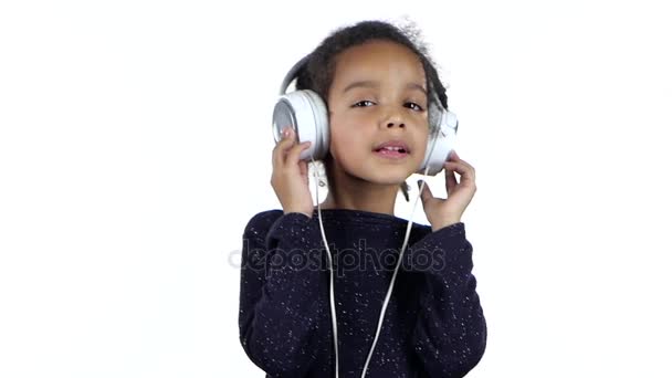 Niño de un afroamericano escucha la música en los auriculares. Fondo blanco. Movimiento lento — Vídeo de stock