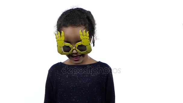 Bebé de una chica afroamericana bailando con gafas graciosas. Fondo blanco. Movimiento lento — Vídeos de Stock