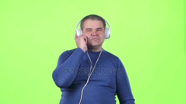 Mn は、ヘッドホンで音楽を聴いています。緑色の画面。スローモーション — ストック動画