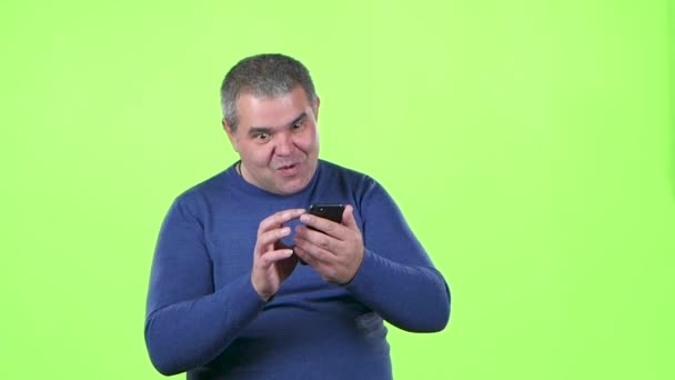 男は、メッセージのための電話を見ています。緑色の画面。スローモーション — ストック動画
