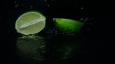 Kireç iki dilim halatları kesin. Siyah arka plan. Ağır çekim