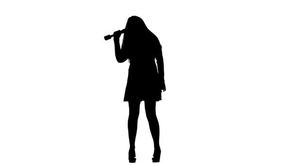 Vrouw zingt brandbommen liedjes in de microfoon. Witte achtergrond. Silhouet. Slow motion — Stockvideo
