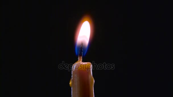 Рука с зажигалкой зажигает одну свечу. Чёрный фон. Закрыть — стоковое видео