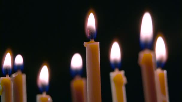 Candles burn, a beautiful orange flame. Black background. Close up — Stock Video