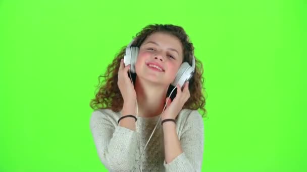 Το παιδί ακούει τη μουσική στα ακουστικά. Πράσινη οθόνη — Αρχείο Βίντεο