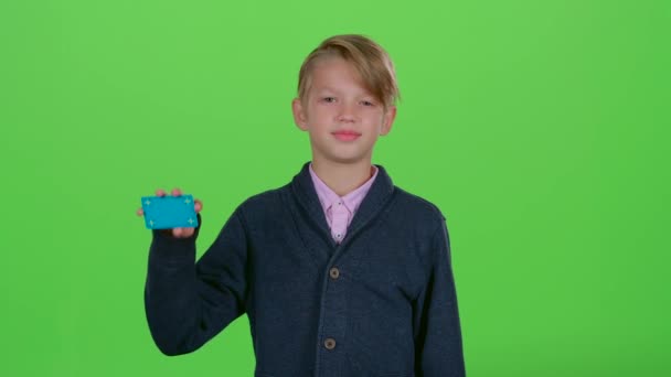 Child boy raises his hand and shows the card on a green screen — Stock Video