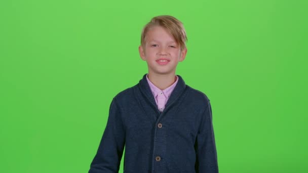 Niño con una tarjeta de crédito lleva una mano de lado a lado en una pantalla verde — Vídeos de Stock