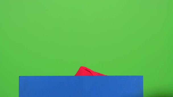 Niño fuera de esconderse detrás de un cartel azul en una pantalla verde — Vídeo de stock