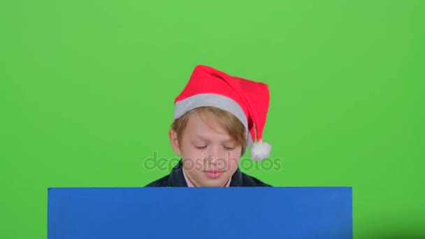 Adolescente en un sombrero rojo aparece de un tablero en una pantalla verde — Vídeos de Stock