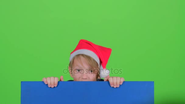 Teen in cap rises holding hands for the board on a green screen — Stock Video