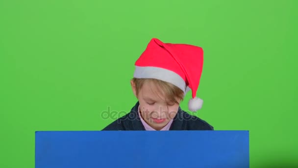 Мальчик появился из-за синего плаката, чтобы посмотреть, как он качает головой и снова прячется. Зеленый экран — стоковое видео