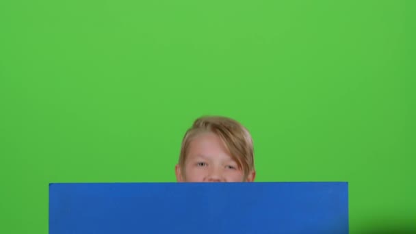 Menino em jumper emerge de trás da placa e acenando em uma tela verde — Vídeo de Stock