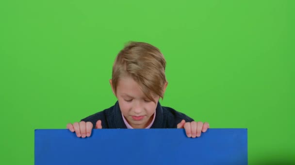 Der kleine Junge tauchte hinter einem blauen Plakat auf, um sich erneut zu verstecken. Green Screen — Stockvideo