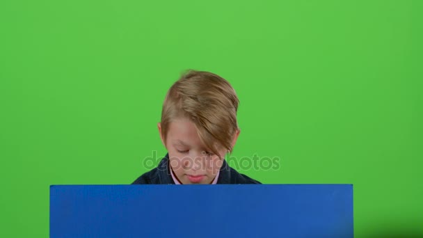 Teenager peeks out from behind the boards and shows dislike on a green screen — Stock Video