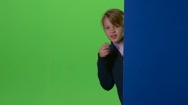 Tonåringen kikar ut bakifrån och ombord på kurvor i ansiktet på en grön skärm — Stockvideo