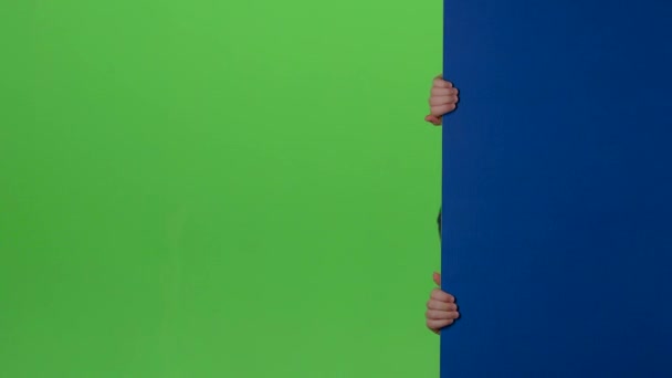 Подросток выглядывает из стороны в сторону доски и демонстрирует неприязнь на зеленом экране — стоковое видео