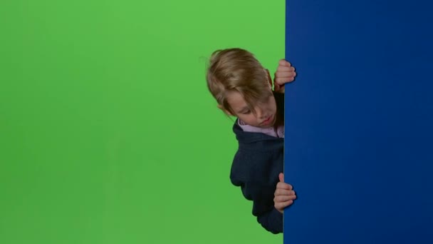 Дитячий хлопчик з'являється з боку дошки і показує нелюбов, а потім як на зеленому екрані — стокове відео