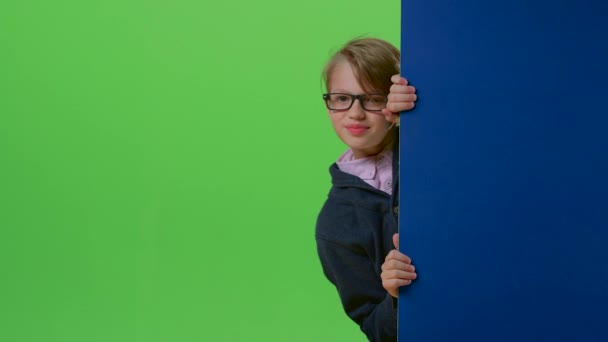 Chłopiec dziecko pojawia się od strony płyty, trzymając ręce w przód na zielony ekran — Wideo stockowe